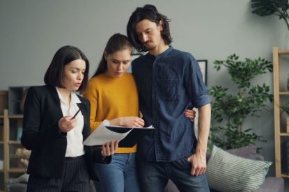 Couple and real estate agent reviewing mortgage documents for home buying.
